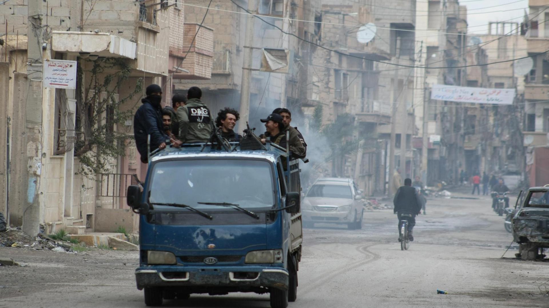 Rebellen stehen auf der Ladefläche eines Pick-ups und fahren am 10.03.2014 durch die ost-syrische Stadt Deir al-Sor. PHOTO / AHMAD ABOUD