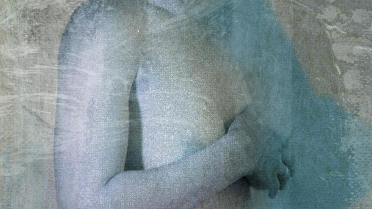 Eine Frau legt schützend einen Arm vor ihre nackte Brust. Eine Frau legt schützend einen Arm vor ihre nackte Brust.