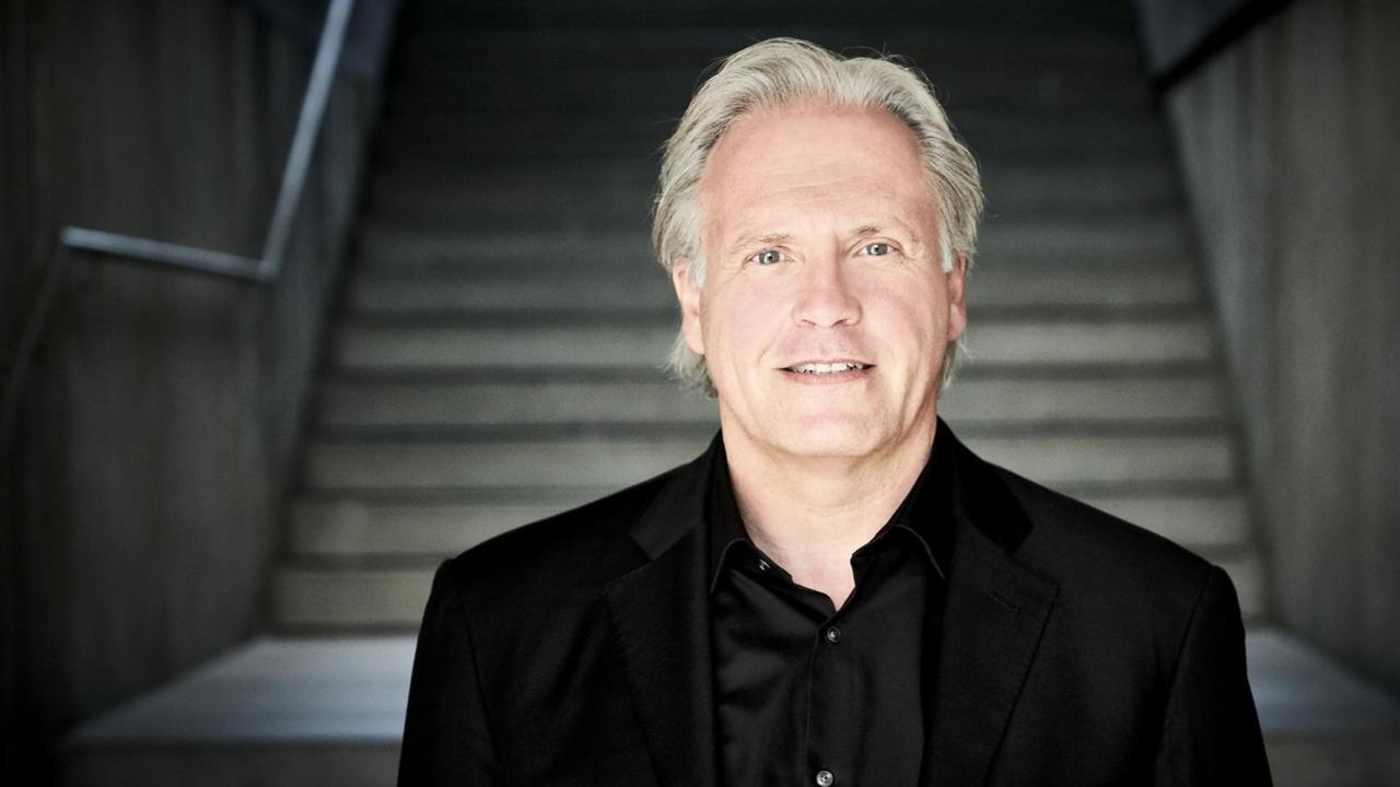 Der Dirigent Markus Stenz vor einer Treppe stehend Der Dirigent Markus Stenz vor einer Treppe stehend