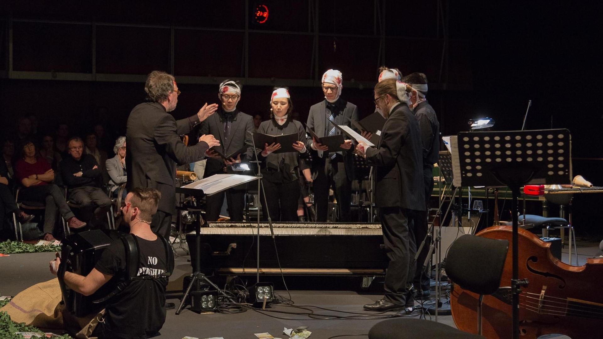Das Bild zeigt eine Szene mit Musikern mit bandagierten Köpfen und mit dem Sarg, dem der Dirigent entstieg. Das Bild zeigt eine Szene mit Musikern mit bandagierten Köpfen und mit dem Sarg, dem der Dirigent entstieg.