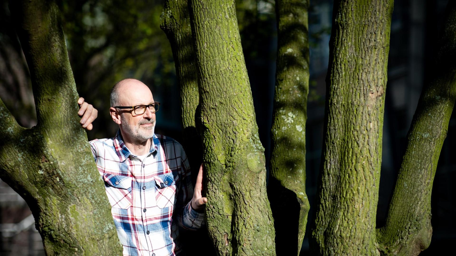 Das Foto zeigt den Förster und Bestseller-Autor Peter Wohlleben, wie er zwischen zwei Bäumen steht. Das Foto zeigt den Förster und Bestseller-Autor Peter Wohlleben, wie er zwischen zwei Bäumen steht.