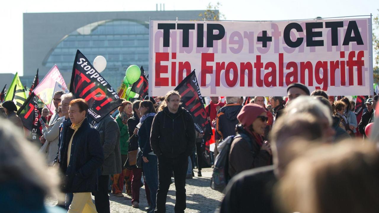 Ein Transparent mit der Aufschrift "TTIP + CETA Ein Frontalangriff" ist bei einer Demonstration gegen das transatlantische Handelsabkommen TTIP (USA) und Ceta (Kanada) am 10.10.2015 in Berlin zu sehen. Ein Transparent mit der Aufschrift "TTIP + CETA Ein Frontalangriff" ist bei einer Demonstration gegen das transatlantische Handelsabkommen TTIP (USA) und Ceta (Kanada) am 10.10.2015 in Berlin zu sehen.