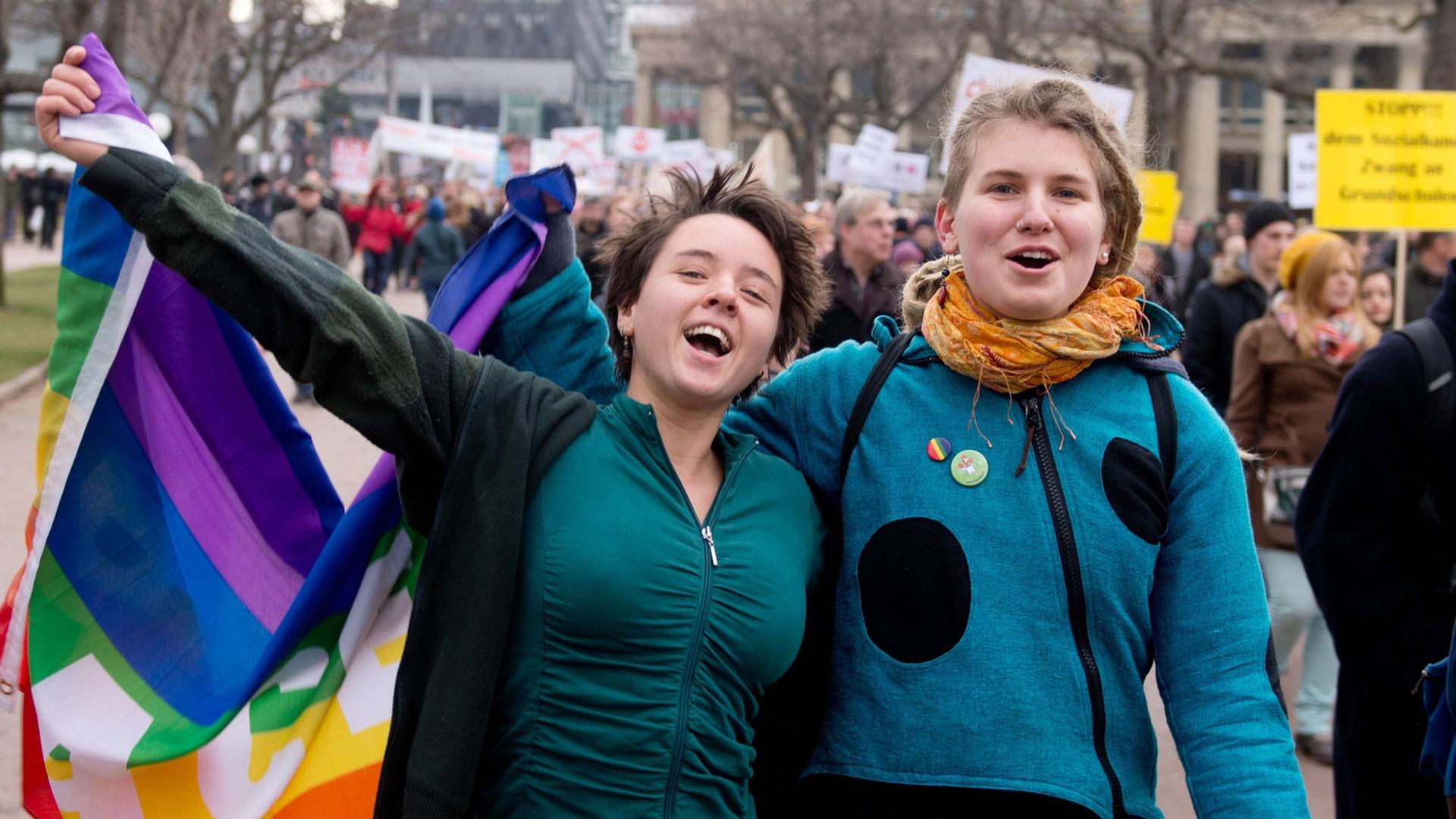Zwei Befürworter der Aufwertung des Themas Homosexualität im Schulunterricht in Baden-Württemberg gehen am 01.02.2014 bei einer Demonstration in Stuttgart (Baden-Württemberg) über den Schlossplatz, in der Hand eine Regenbogenfahne. Zwei Befürworter der Aufwertung des Themas Homosexualität im Schulunterricht in Baden-Württemberg gehen am 01.02.2014 bei einer Demonstration in Stuttgart (Baden-Württemberg) über den Schlossplatz, in der Hand eine Regenbogenfahne.