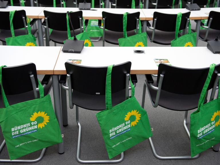Stoffbeutel mit dem Grünen-Logo hängen im vor Beginn einer Fraktionssitzung 2012 im Bundestag über den Stuhllehnen.