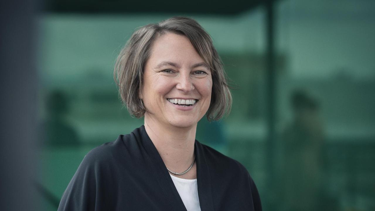 Unternehmensberaterin, Betriebswirtschaftlerin und Wirtschaftsinformatikerin Henrike von Platen steht in schwarzem Jackett vor dunkelgrünem Hintergrund Unternehmensberaterin, Betriebswirtschaftlerin und Wirtschaftsinformatikerin Henrike von Platen steht in schwarzem Jackett vor dunkelgrünem Hintergrund