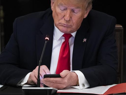 US-Präsident Donald Trump schaut auf sein Smartphone.