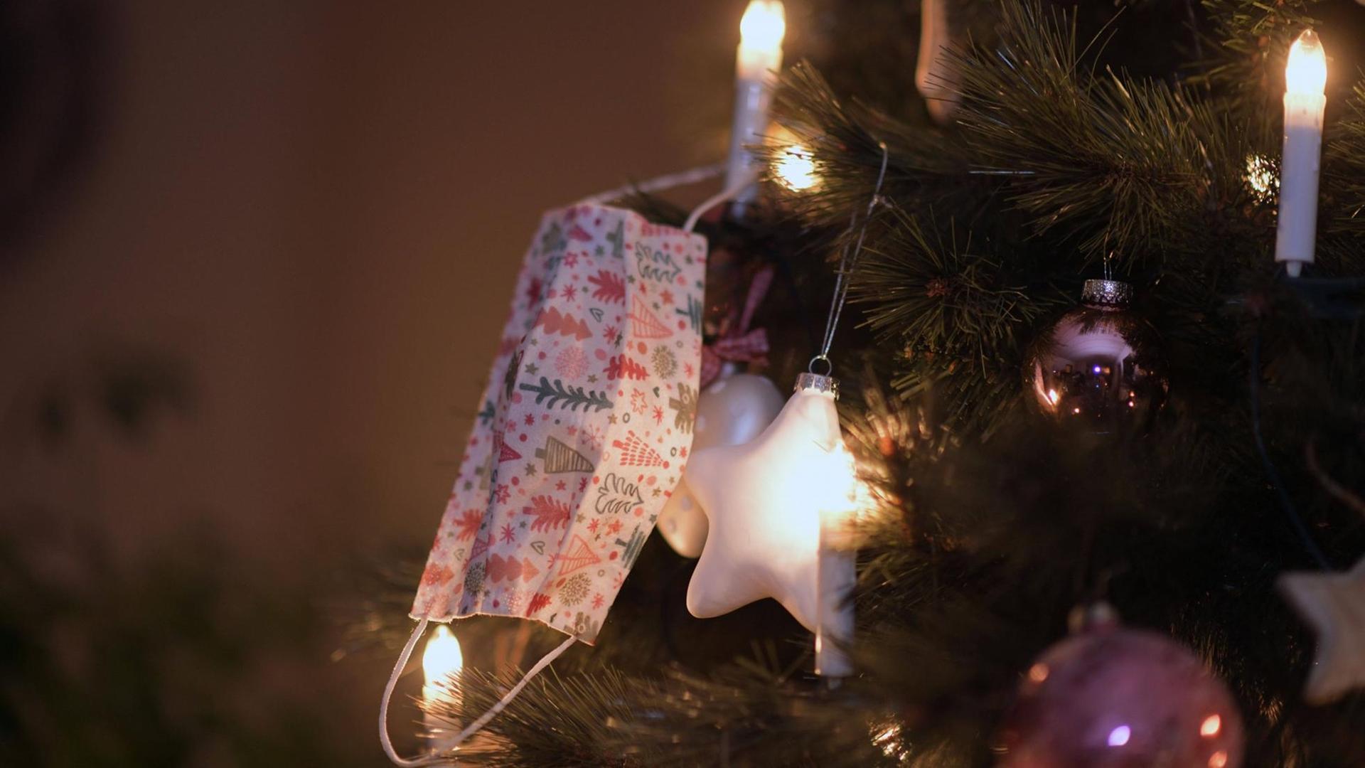 23.11.2020, Symbolbild, Am Weihnachstbaum im Wohnzimmer hängt ein Mund-Nasen-Schutz. 23.11.2020, Symbolbild, Am Weihnachstbaum im Wohnzimmer hängt ein Mund-Nasen-Schutz.