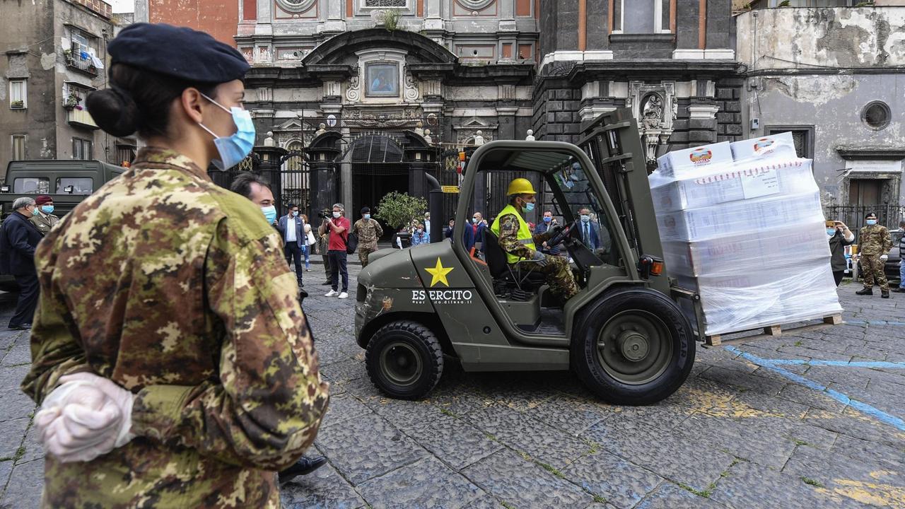 Soldaten mit Schutzmasken transportieren mit einem Gabelstapler Essen vor einer Kirche in Neapel Soldaten mit Schutzmasken transportieren mit einem Gabelstapler Essen vor einer Kirche in Neapel