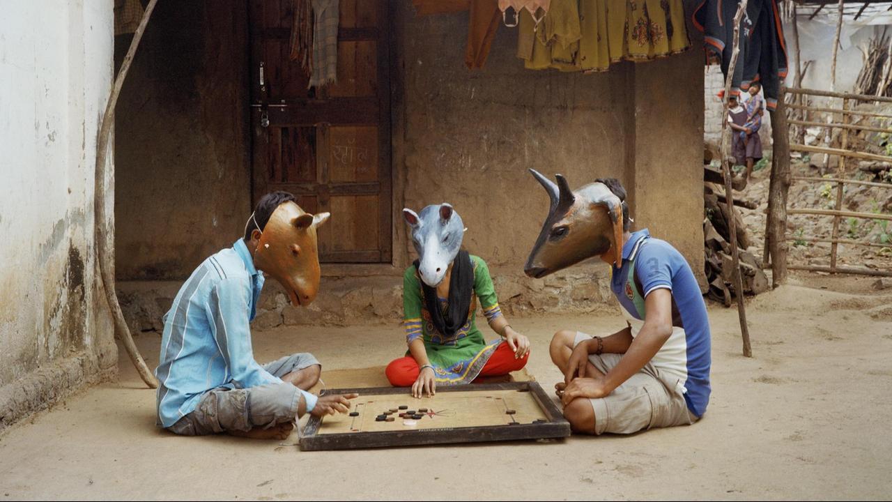 Drei Menschen sitzen mit Masken auf dem Boden und spielen.