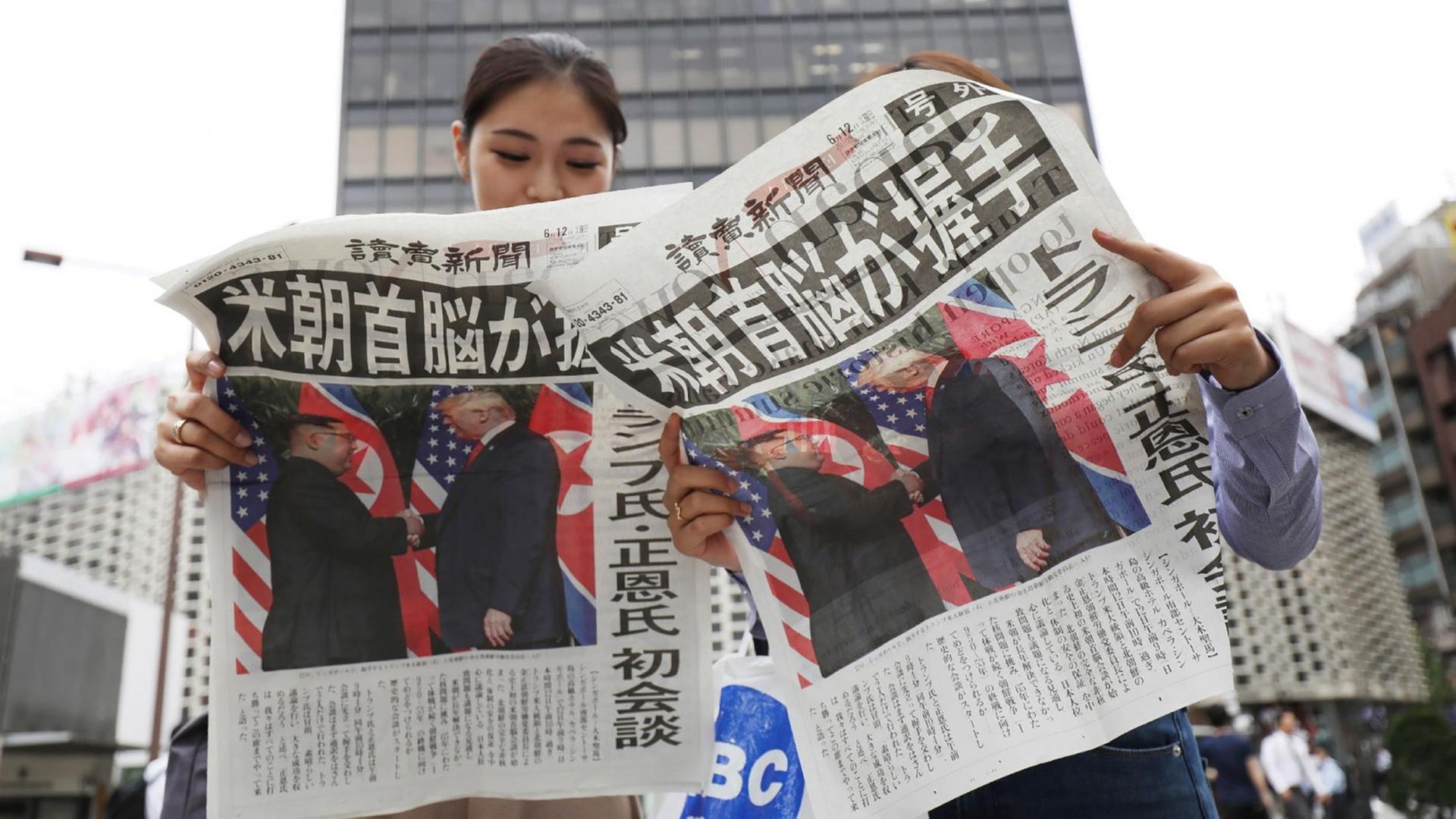 Passanten in Tokio lesen die in einer Sonderausgabe über das Treffen zwischen dem US-Präsidenten und Nordkoreas Machthaber Passanten in Tokio lesen die in einer Sonderausgabe über das Treffen zwischen dem US-Präsidenten und Nordkoreas Machthaber