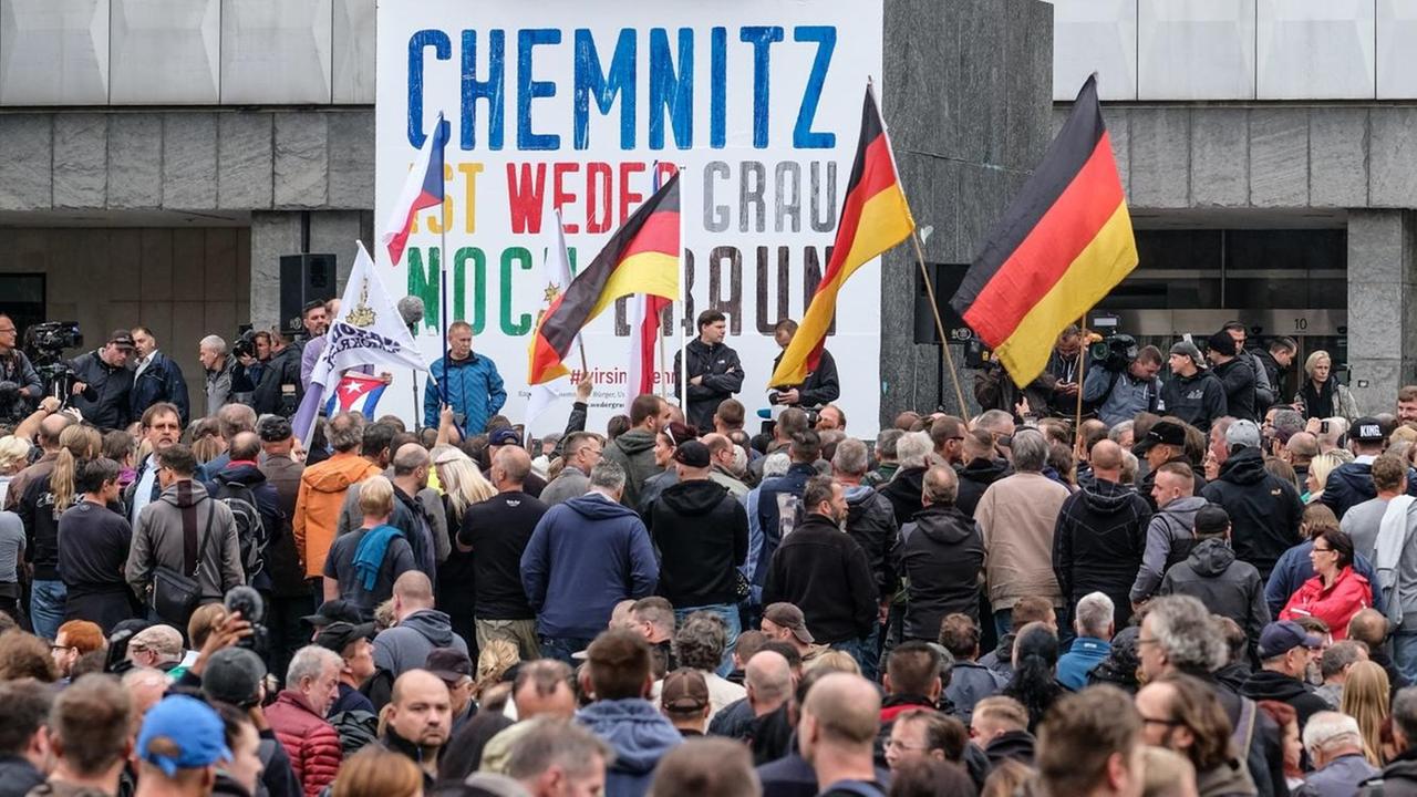 Demonstranten stehen in Chemnitz vor der Karl-Marx-Statue. Darauf ein Spruchband: "Chemnitz ist weder grau noch braun." Demonstranten stehen in Chemnitz vor der Karl-Marx-Statue. Darauf ein Spruchband: "Chemnitz ist weder grau noch braun."
