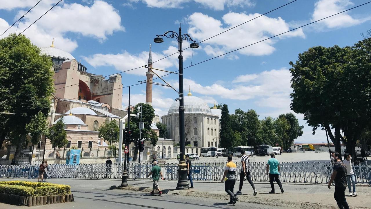 Mehrere Männer laufen einzeln über die Straße, mit Blick auf die Hagia Sophia.