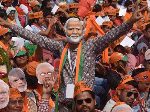 Inder tragen auf einer Demonstration Masken mit dem Bild von Indiens Premierminister Narendra Modi.