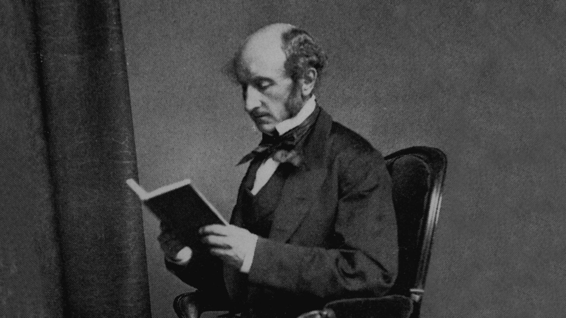 Porträt von John Stuart Mill (1806–1873). Er sitzt in einem Stuhl in liest ein Buch. Porträt von John Stuart Mill (1806–1873). Er sitzt in einem Stuhl in liest ein Buch.