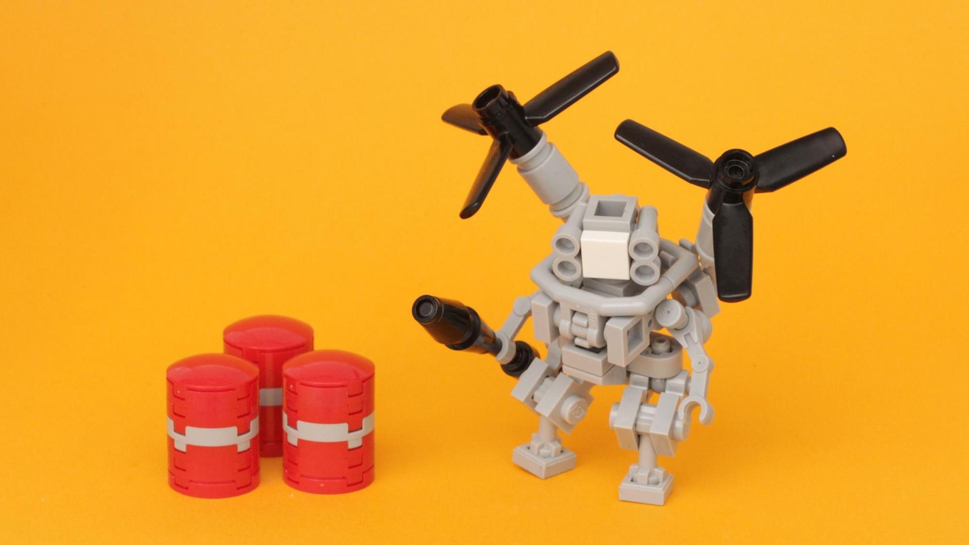 Lego-Roboter mit Propellern neben drei kleinen, roten Fässern vor einem gelben Hintergrund Lego-Roboter mit Propellern neben drei kleinen, roten Fässern vor einem gelben Hintergrund
