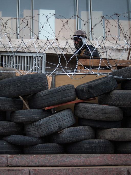 Pro-russische Bewaffnete in Donezk hinter einer Barrikade aus Autoreifen und Stachedraht