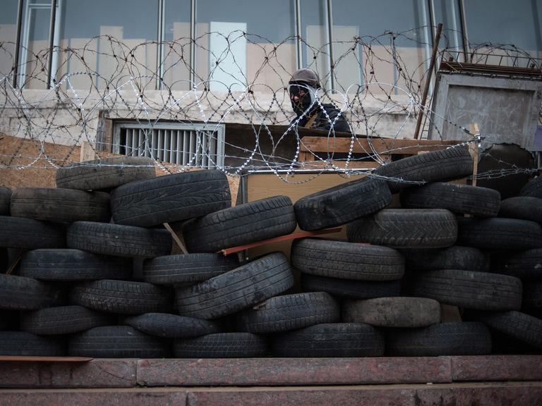Pro-russische Bewaffnete in Donezk hinter einer Barrikade aus Autoreifen und Stachedraht
