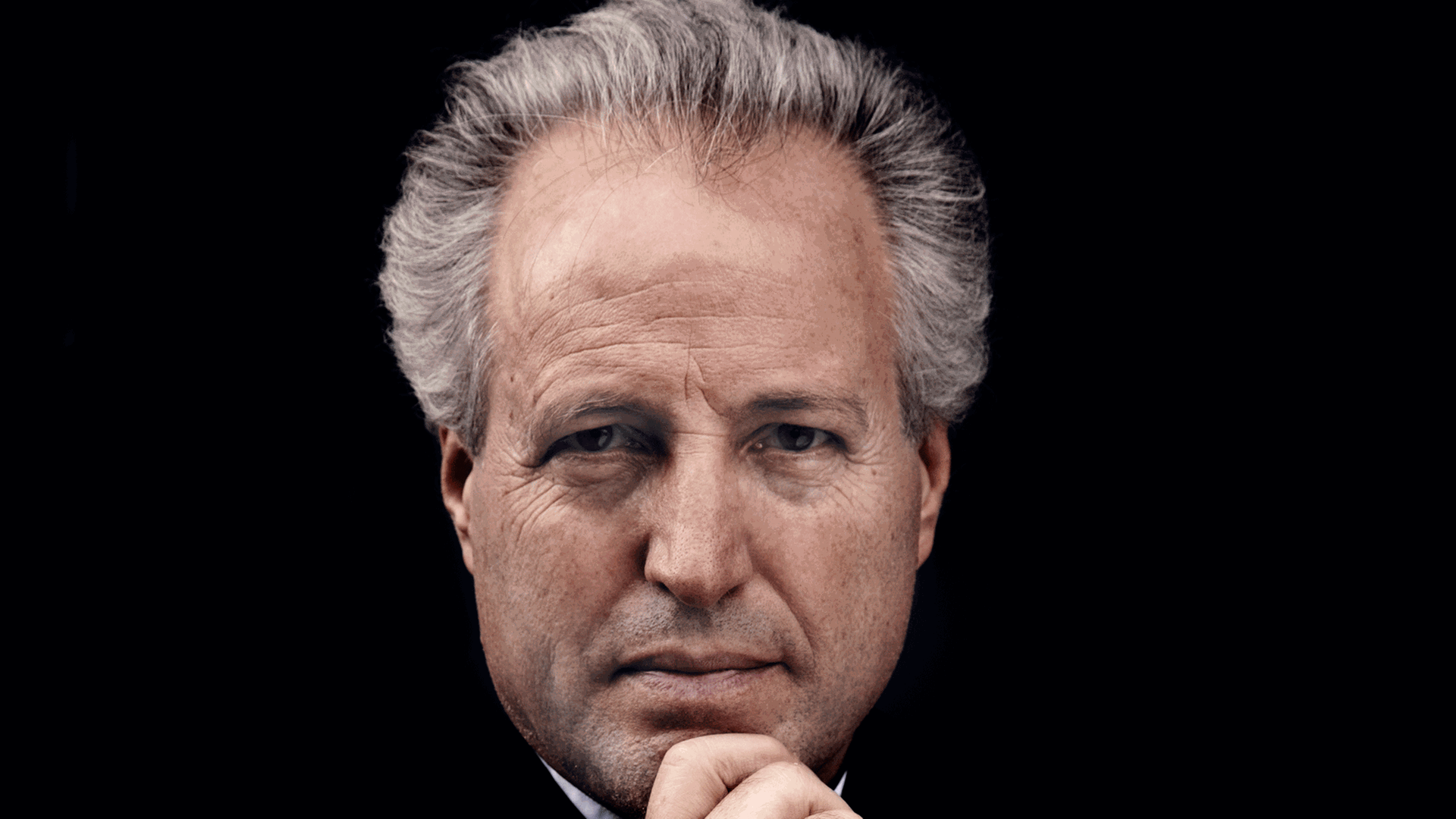 Der Dirigent Manfred Honeck schaut mit aufgestützem Kinn in der Hand direkt in die Kamera. Der Dirigent Manfred Honeck schaut mit aufgestützem Kinn in der Hand direkt in die Kamera.