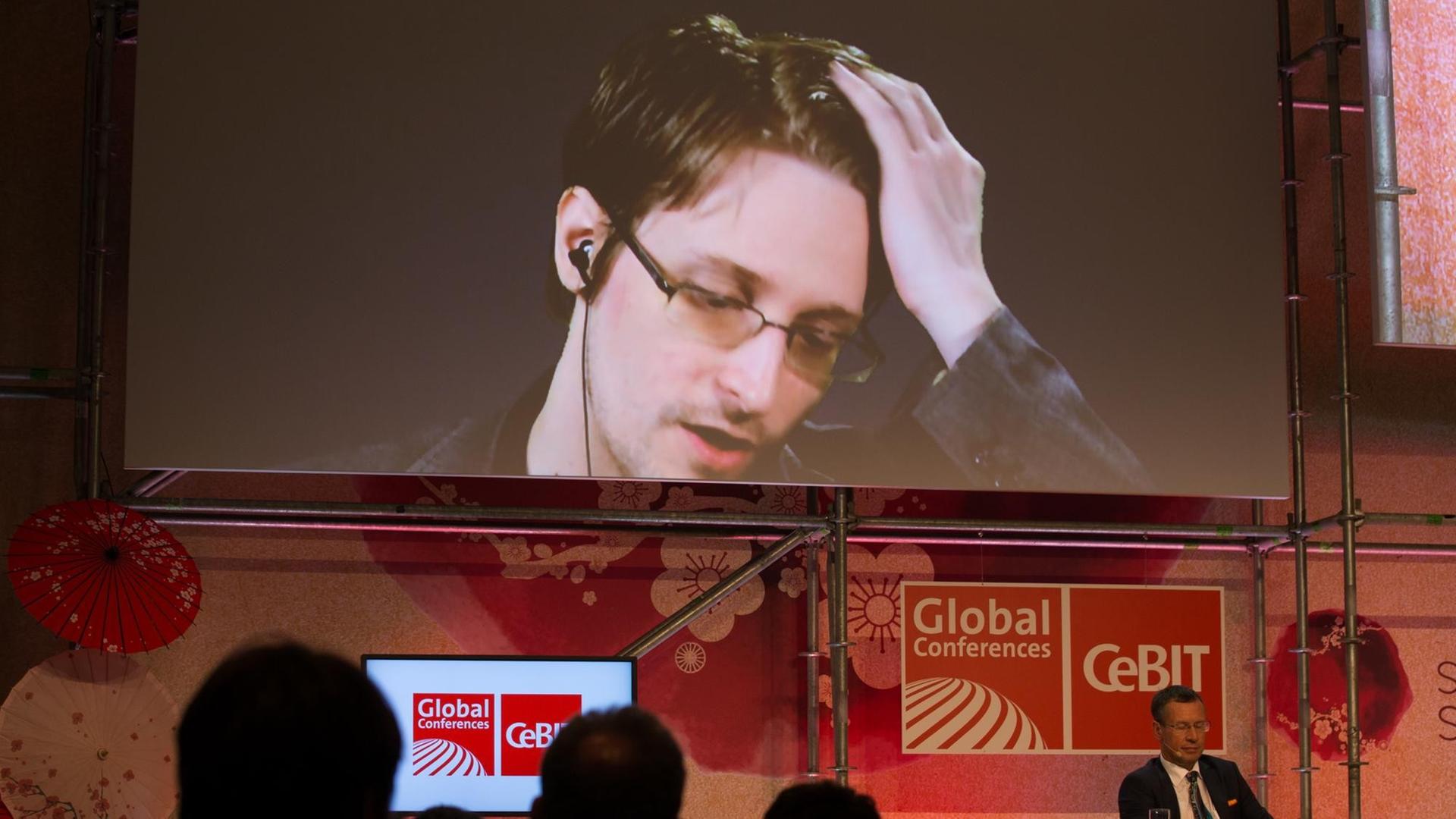 Der US-amerikanische Whistleblower und ehemalige CIA-Mitarbeiter Edward Snowden spricht am 21.03.2017 bei der IT-Messe CeBIT in Hannover (Niedersachsen) auf einer Videowand. Die IT-Messe CeBIT will ihr Fachpublikum mit konkreten Anwendungsbeispielen für neue Technologien überzeugen. Zu der fünftägigen Veranstaltung (20.-24. März) mit über 3000 Ausstellern aus 70 Ländern werden rund 200000 Besucher erwartet. Partnerland ist Japan. Der US-amerikanische Whistleblower und ehemalige CIA-Mitarbeiter Edward Snowden spricht am 21.03.2017 bei der IT-Messe CeBIT in Hannover (Niedersachsen) auf einer Videowand. Die IT-Messe CeBIT will ihr Fachpublikum mit konkreten Anwendungsbeispielen für neue Technologien überzeugen. Zu der fünftägigen Veranstaltung (20.-24. März) mit über 3000 Ausstellern aus 70 Ländern werden rund 200000 Besucher erwartet. Partnerland ist Japan.