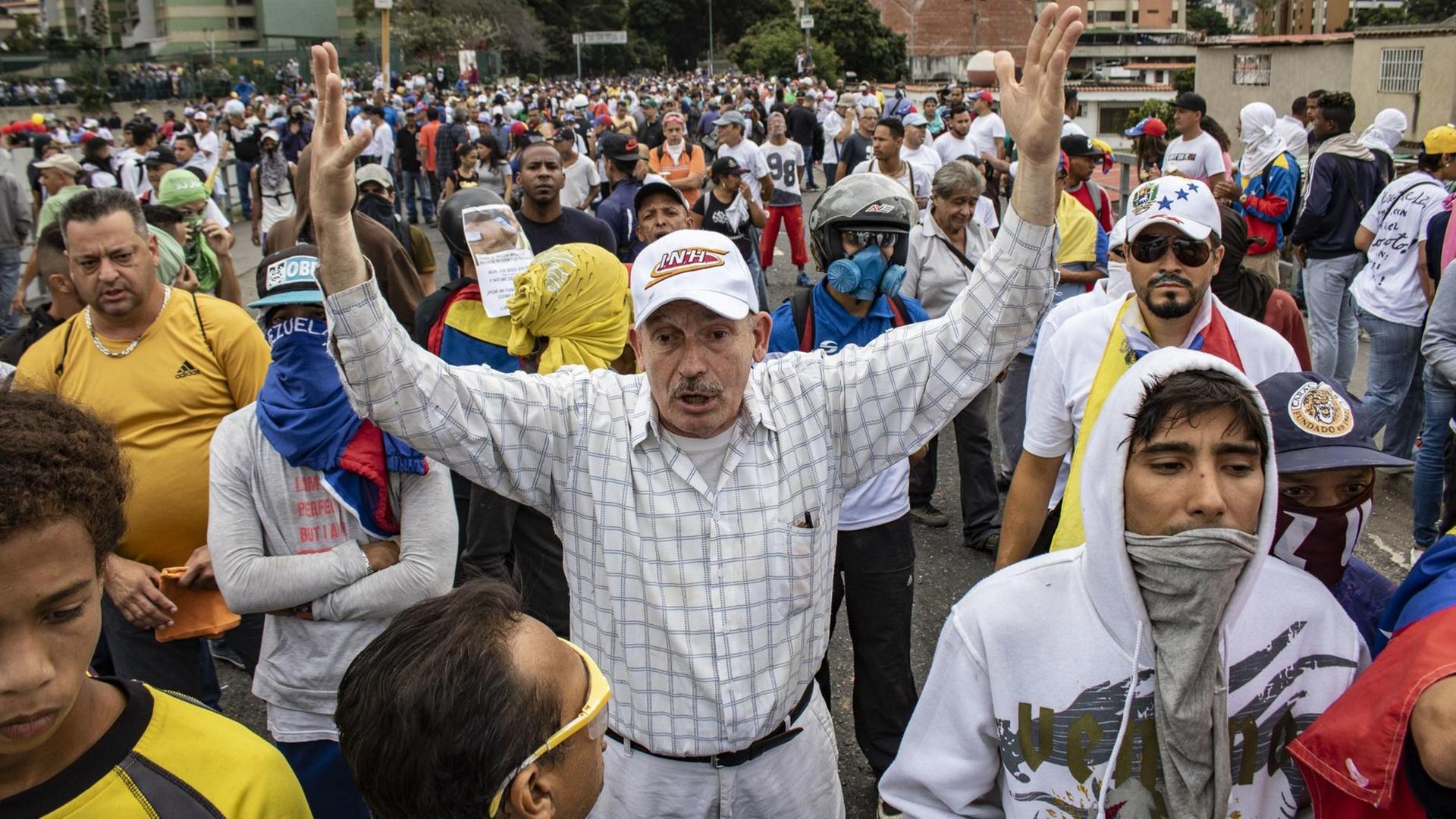 Ein Mann hebt die Arme hoch bei einem Protest gegen die Regierung von Präsidenten Maduro. Ein Mann hebt die Arme hoch bei einem Protest gegen die Regierung von Präsidenten Maduro.