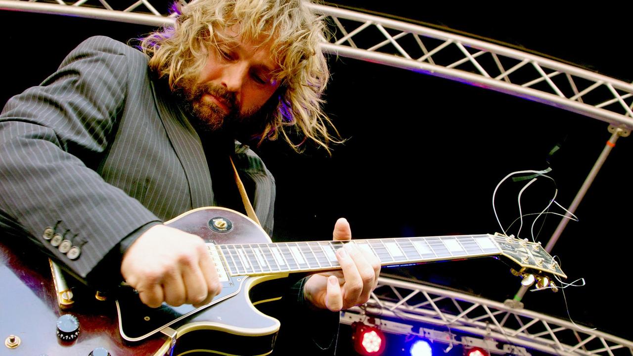 Ein Mann steht auf einer Bühne und spielt Gitarre. Ein Mann steht auf einer Bühne und spielt Gitarre.