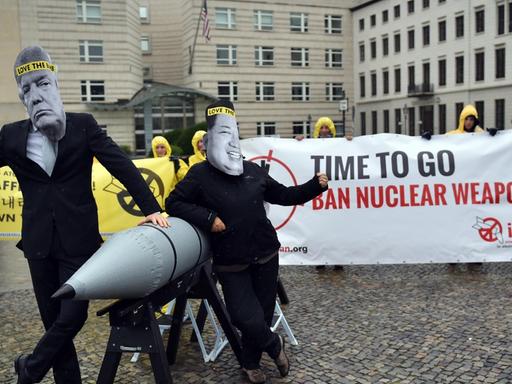 Aktivisten der Internationalen Kampagne zur Abschaffung von Atomwaffen (ICAN) protestieren vor der amerikanischen Botschaft in Berlin mit Masken des nordkoreanischen Machthabers Jong-un (r) und des US-Präsidenten Trump gegen den Konflikt zwischen Nordkorea und den USA.