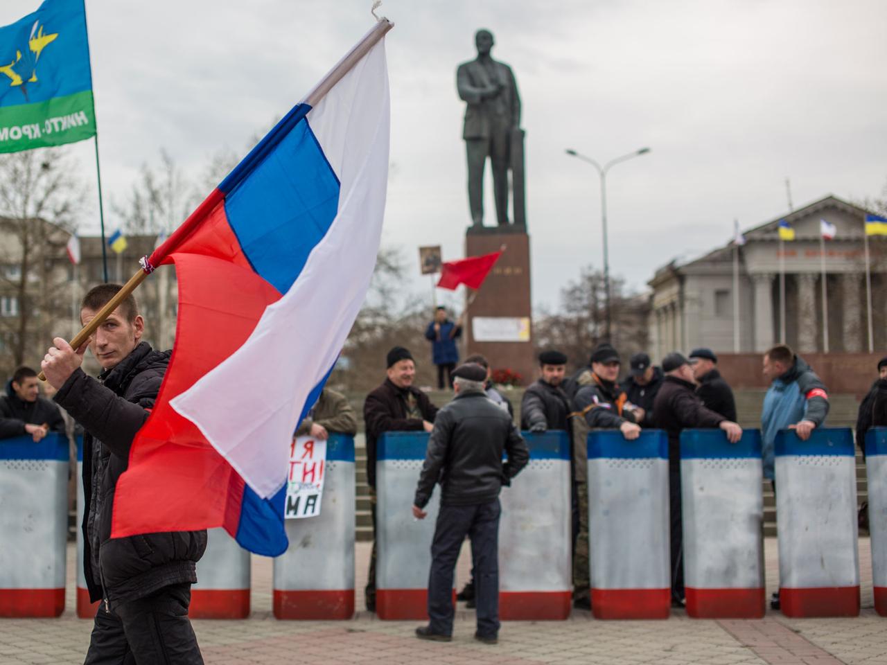 Ein Demonstrant trägt eine russische Flagge. Ein Demonstrant trägt eine russische Flagge.