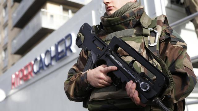 Ein Soldat steht mit einem Maschinengewehr vor einem Supermarkt für koschere Lebensmittel in Paris.