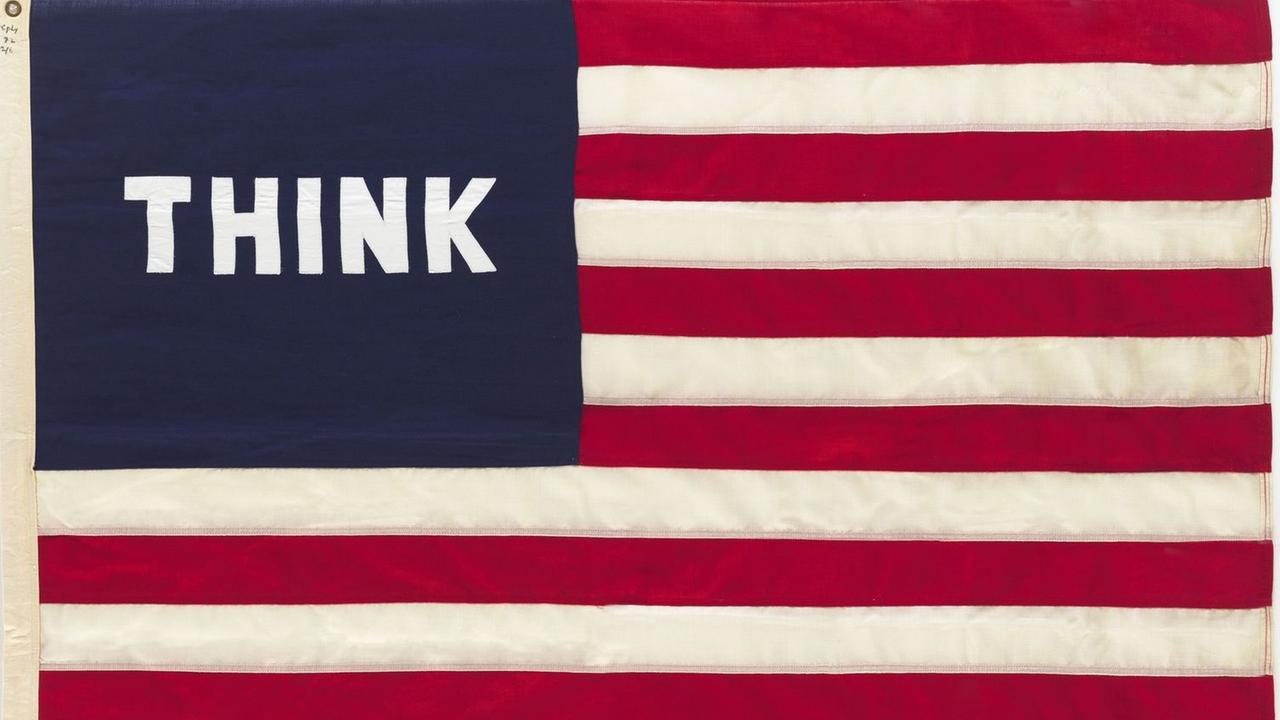 Das Werk "Imaginary Flag for U.S.A." von William N Copley, eine amerikanische Flagge, in deren linken oberen Ecke statt der weißen Sterne auf blauem Grund das Wort THINK zu sehen ist Das Werk "Imaginary Flag for U.S.A." von William N Copley, eine amerikanische Flagge, in deren linken oberen Ecke statt der weißen Sterne auf blauem Grund das Wort THINK zu sehen ist