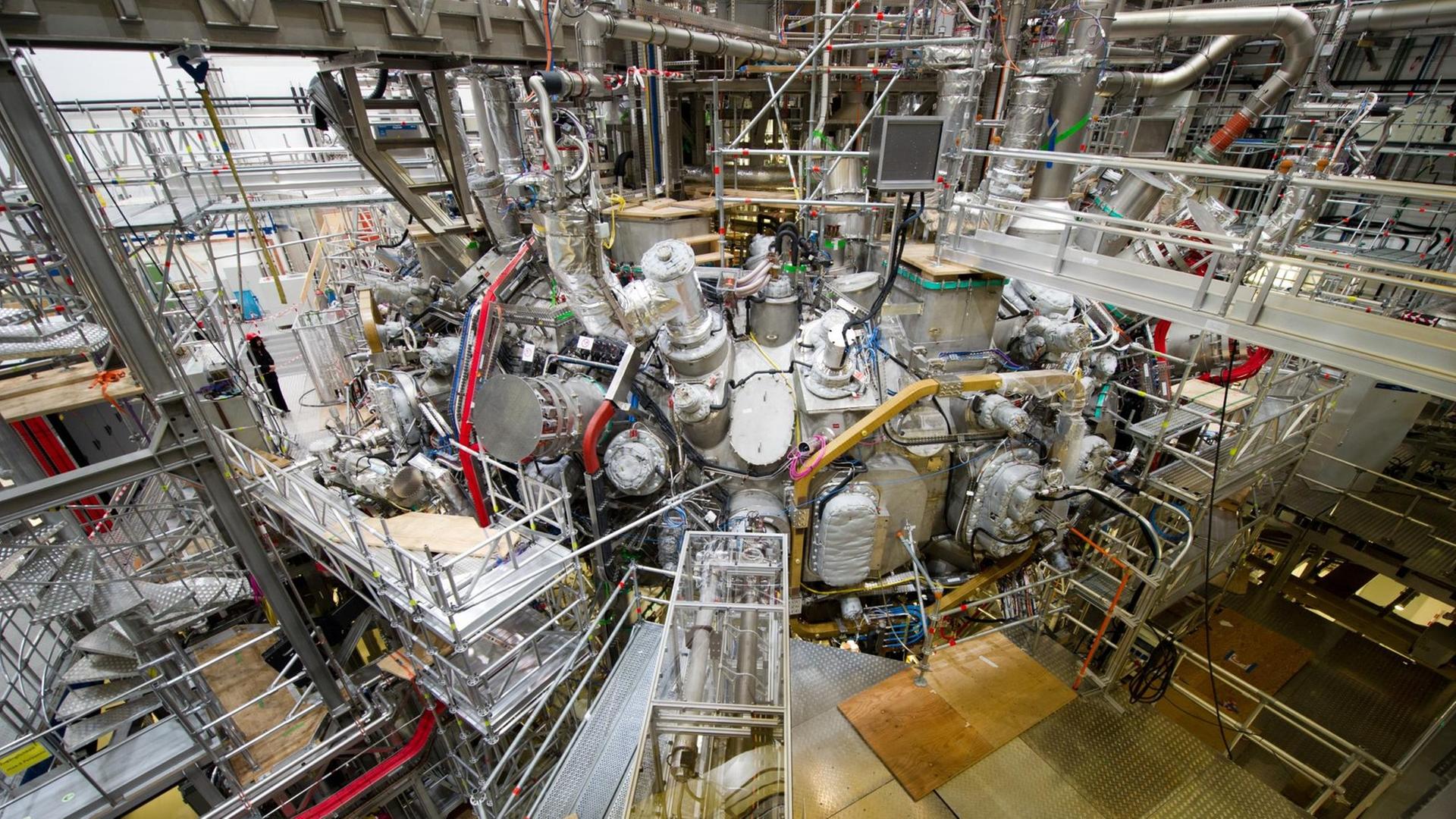 In der Kernfusionsforschungsanlage "Wendelstein 7-X" in Greifswald (Mecklenburg-Vorpommern) ist am 10.12.2015 das erste Plasma erzeugt worden. Das Bild zeigt ein großes Gebilde aus Metall in einer Halle.