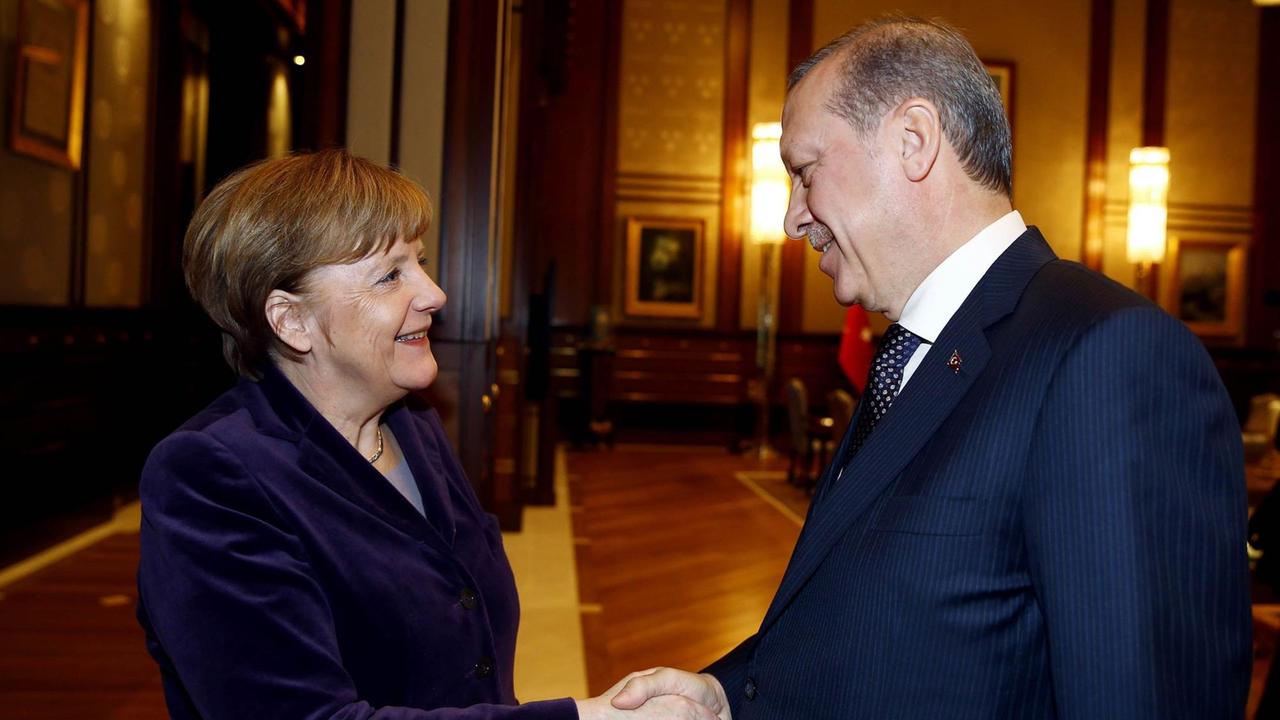 Angela Merkel und der türkische Präsident Recep Tayyip Erdogan schütteln sich die Hände und lächeln. Angela Merkel und der türkische Präsident Recep Tayyip Erdogan schütteln sich die Hände und lächeln.