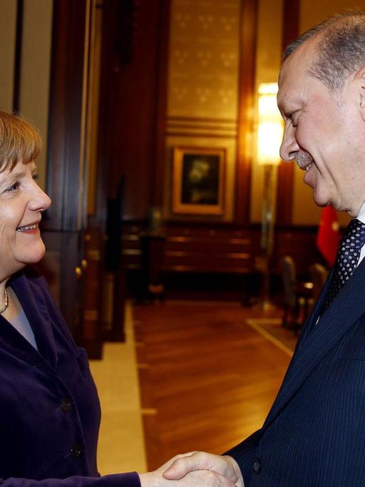 Angela Merkel und der türkische Präsident Recep Tayyip Erdogan schütteln sich die Hände und lächeln.