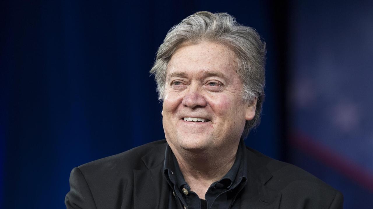 Bannon sitzt auf einem Podium und lächelt in die Kamera. Bannon sitzt auf einem Podium und lächelt in die Kamera.