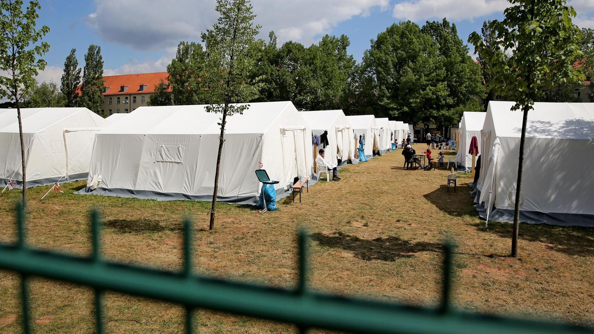 Flüchtlinge sitzen vor weißen Zelten in der Erstaufnahmeeinrichtung Chemnitz