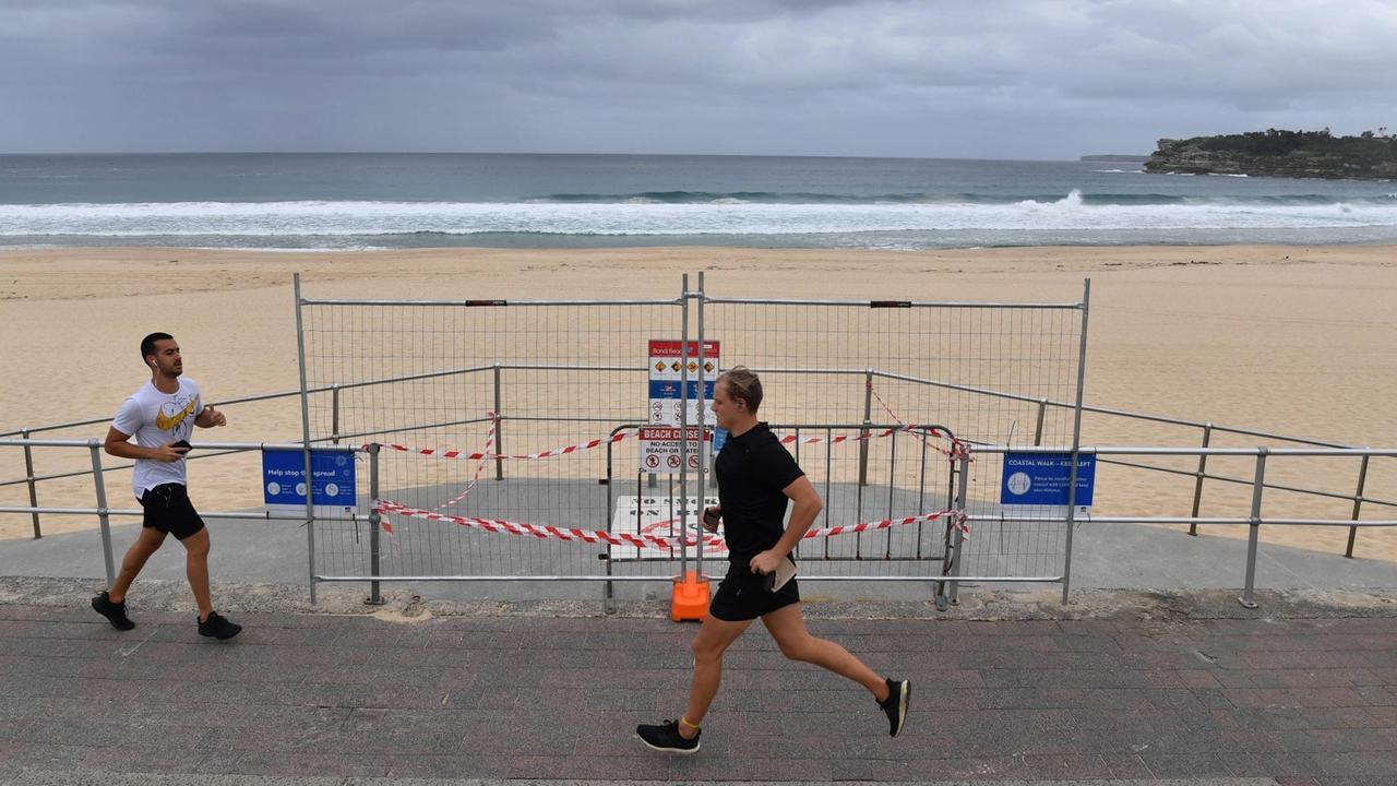 An der Promenade vor einem menschenleeren Strand laufen zwei Jogger aneinander vorbei. An der Promenade vor einem menschenleeren Strand laufen zwei Jogger aneinander vorbei.