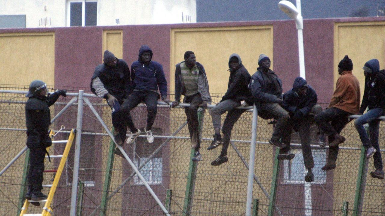 Ein spanischer Polizist spricht mit den Flüchtlingen, die auf dem Grenzzaun in Melilla sitzen. Ein spanischer Polizist spricht mit den Flüchtlingen, die auf dem Grenzzaun in Melilla sitzen.