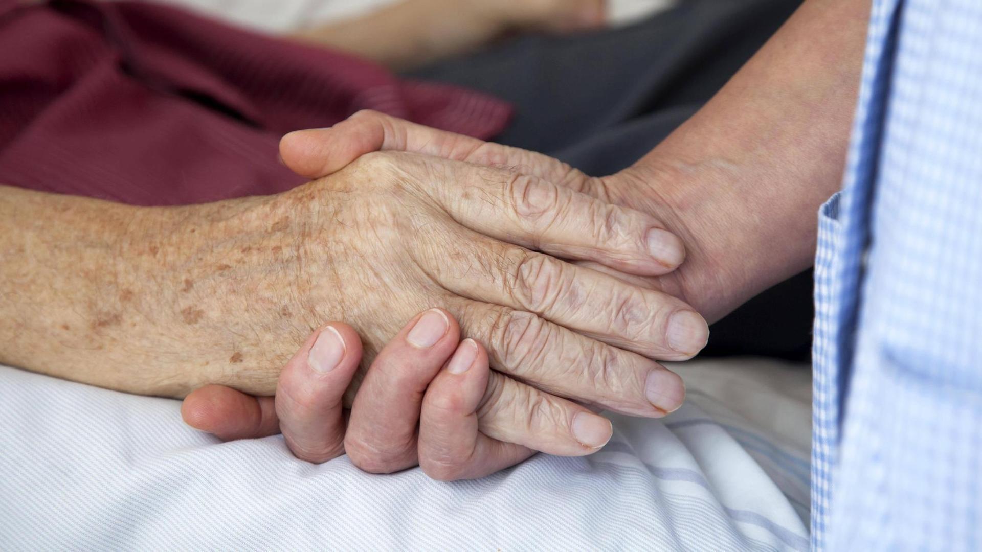15.07.2010, Nordrhein-Westfalen, Deutschland - Hospiz. Die Hand einer Pflegerin haelt die Hand eines sterbenden Mannes. (QF, ältere, älterer, berühren, Berührung, bettlägerig, europäisch, Fürsorge, fürsorglich, Hände, häusliche Pflege, Menschenwürde, menschenwürdiges Sterben, Nähe, trösten) 00X110715D001.JPG MODEL RELEASE: YES,RELEASE: 15.07.2010, Nordrhein-Westfalen, Deutschland - Hospiz. Die Hand einer Pflegerin haelt die Hand eines sterbenden Mannes. (QF, ältere, älterer, berühren, Berührung, bettlägerig, europäisch, Fürsorge, fürsorglich, Hände, häusliche Pflege, Menschenwürde, menschenwürdiges Sterben, Nähe, trösten) 00X110715D001.JPG MODEL RELEASE: YES,RELEASE: