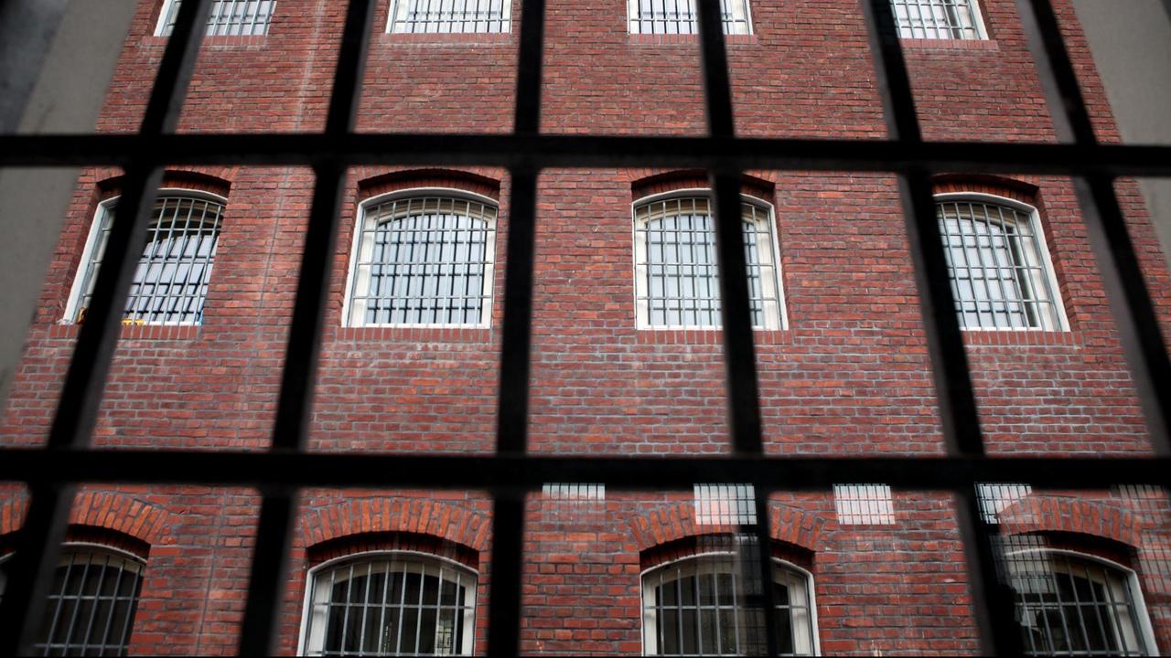 Blick durch ein vergittertes Fenster auf ein altes Hafthaus in der JVA Waldheim.