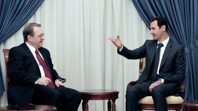 Der syrische Präsident Baschar al Assad spricht im Dezember 2014 mit einem russischen Gesandten, dem stellvertretenden Außenminister Michail Bogdanow, in Damaskus.