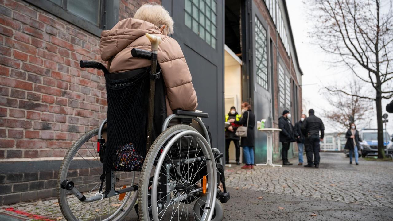 Eine Frau im Rollstuhl steht vor dem Impfzentrum in der Treptow Arena für die Impfung gegen das Corona-Virus an. Eine Frau im Rollstuhl steht vor dem Impfzentrum in der Treptow Arena für die Impfung gegen das Corona-Virus an.