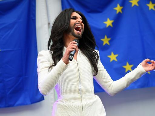 Conchita Wurst singt im Europaparlament in Brüssel vor zwei EU-Flaggen.