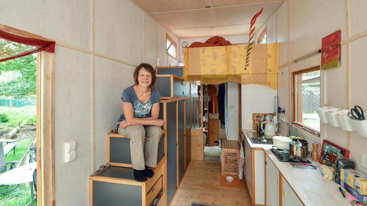 Eine Frau sitzt in einem kleinen, mobilen Haus.