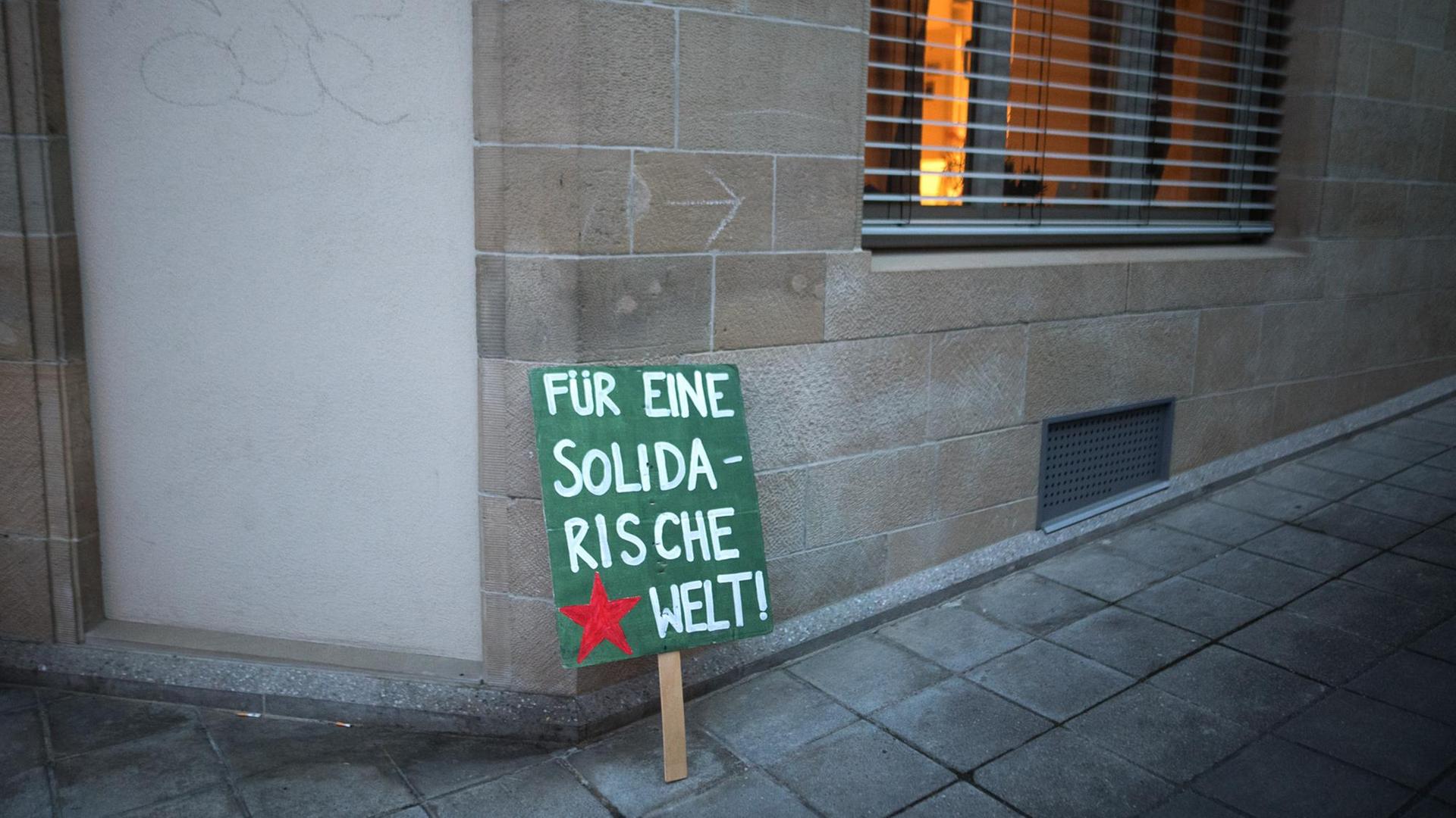 Ein Plakat mit der Aufschrift "Für eine solidarische Welt" steht nach einer Demonstration an eine Hauswand gelehnt. Ein Plakat mit der Aufschrift "Für eine solidarische Welt" steht nach einer Demonstration an eine Hauswand gelehnt.