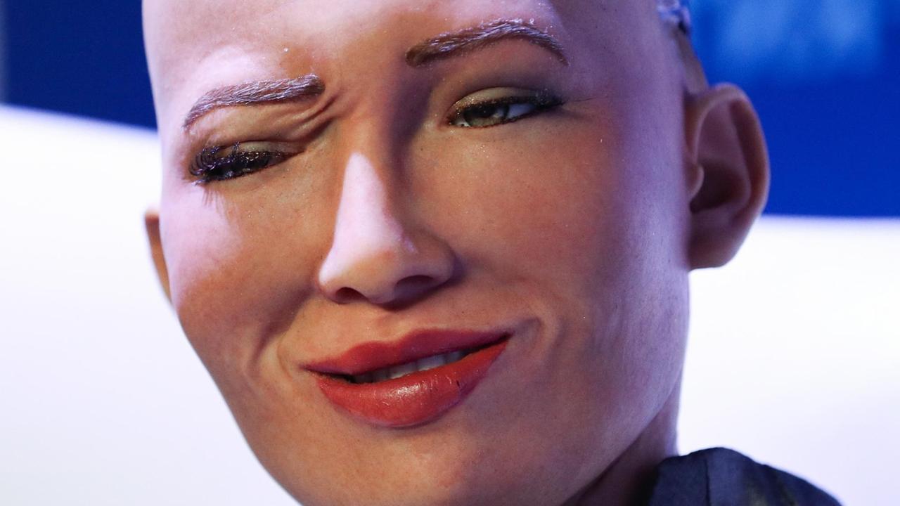 Nahaufnahme des Gesichts von Sophia, einem humanoiden Roboter des Unternehmens Hanson Robotics, mit einem zwinkernden Auge und hochgezogenen Mundwinkeln.