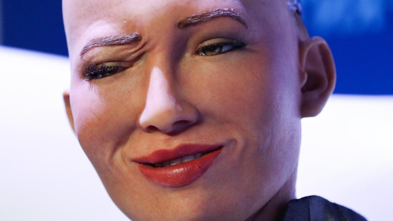 Nahaufnahme des Gesichts von Sophia, einem humanoiden Roboter des Unternehmens Hanson Robotics, mit einem zwinkernden Auge und hochgezogenen Mundwinkeln. Nahaufnahme des Gesichts von Sophia, einem humanoiden Roboter des Unternehmens Hanson Robotics, mit einem zwinkernden Auge und hochgezogenen Mundwinkeln.