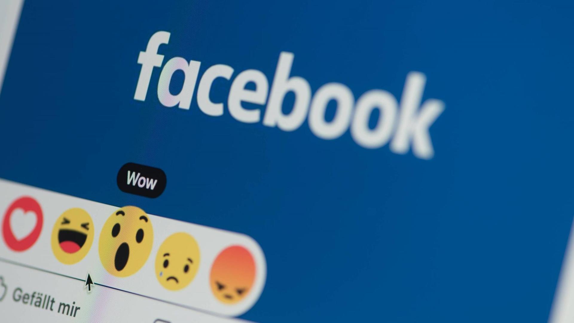 Auf einem Bildschirm erscheint das Logo von Facebook sowie die Symbole für "Gefällt mir", "Wow" usw. Auf einem Bildschirm erscheint das Logo von Facebook sowie die Symbole für "Gefällt mir", "Wow" usw.