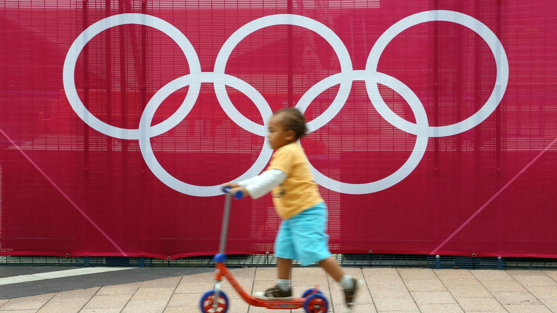 Ein Kind spielt vor den Olympischen Ringen