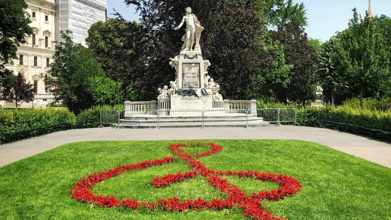 Blauer Himmel über dem Denkmal Mozarts im Park von Wien, vor dem aus roten Blumen ein Notenschlüssel gepflanzt wurde. Blauer Himmel über dem Denkmal Mozarts im Park von Wien, vor dem aus roten Blumen ein Notenschlüssel gepflanzt wurde.