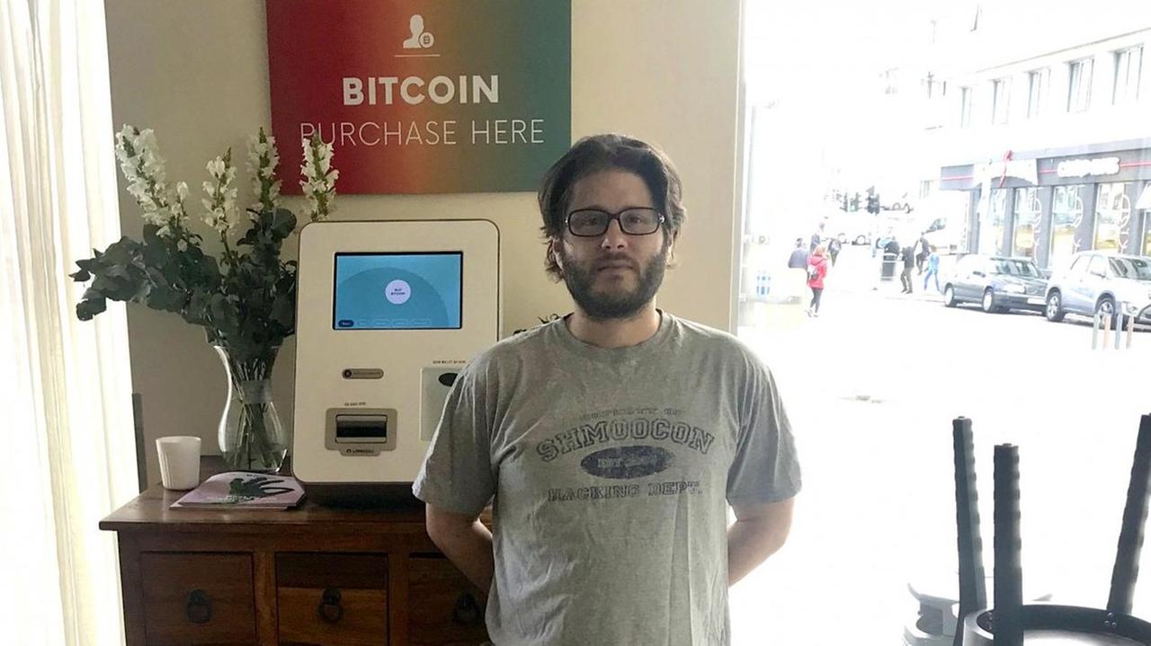 Bitcoin-Unternehmer Jason Scott vor seinem Bitcoin-Automaten in Reykjavik. Ein kleiner, weißer Kasten mit Bildschirm. Bitcoin-Unternehmer Jason Scott vor seinem Bitcoin-Automaten in Reykjavik. Ein kleiner, weißer Kasten mit Bildschirm.