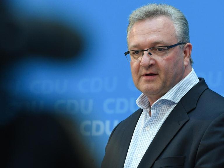 Henkel vor dem blauen CDU-Backdrop, links im Vordergrund sieht man die unscharfe Silhouette eines Fotografen.